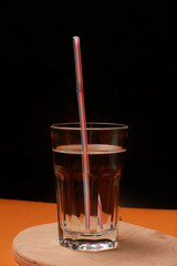 A glass of water with ice and a straw