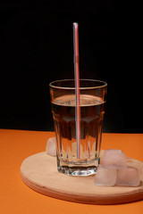 A glass of water with ice and a straw