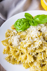Delicious farfalle pasta with pesto sauce on wooden rustic background