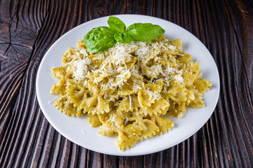 Delicious farfalle pasta with pesto sauce on wooden rustic background