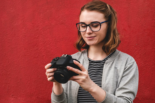 Young female photographer checking her image over a red background