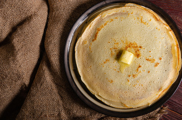 Traditional Russian homemade pancakes on a large round plate in a rustic style.