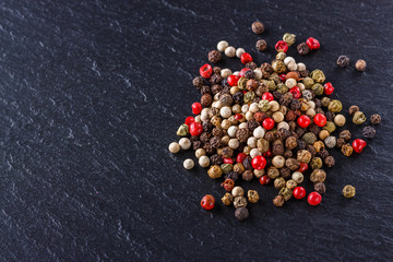 mix of peppercorns on a dark stone background