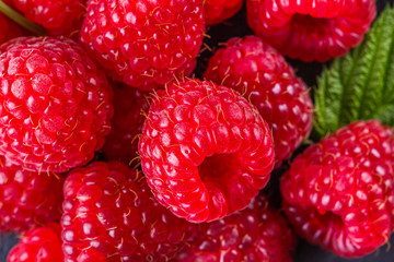 juicy fresh natural raspberries on a dark stone background
