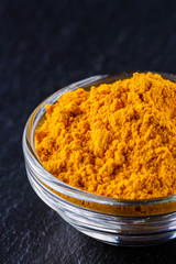 natural turmeric powder on a dark stone background