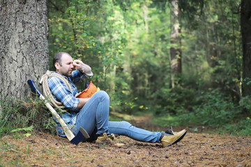 Male lumberjack in the forest. A professional woodcutter inspects trees for felling.