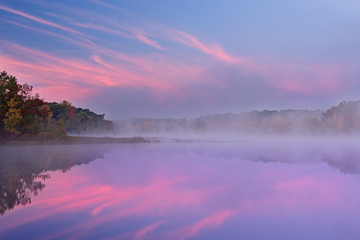Autumn landscape at dawn of the shoreline of Deep Lake with mirrored reflections in calm water, Yankee Springs State Park, Michigan, USA