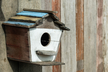 Small handmade wood birdhouse with wooden wall background