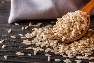 raw brown rice on dark rustic wooden background