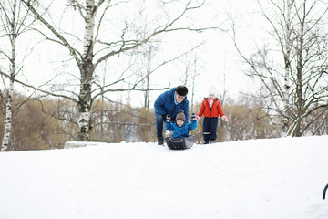 Children in the park in winter. Kids play with snow on the playground. They sculpt snowmen and slide down the hills.