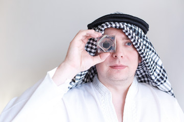 Arab sheikh from Arabia saudi,Emirates holds in hands and looks to drop of black oil of Brent brand in crystal cube.Crisis in financial market, falling,rising prices, quotes, changes in exchange rate