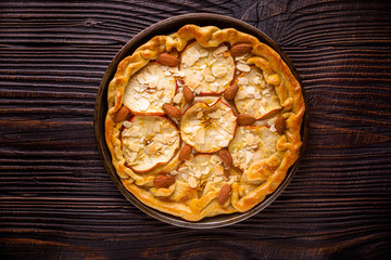crispy apple galette with almonds on rustic wooden background