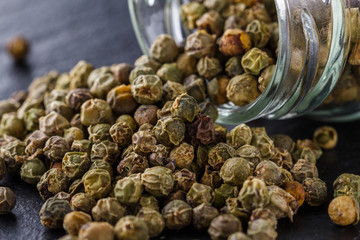 green peppercorns on dark slate stone background