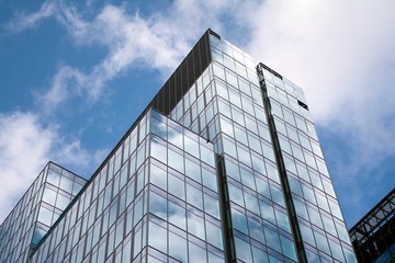 Plakat Modern curtain wall made of glass and steel. Blue sky and clouds reflected in windows of modern office building. 