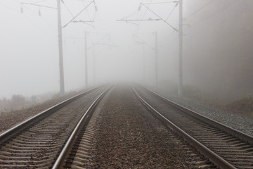 Two parallel tracks of the railway, going into the distance into fog and suspense.
