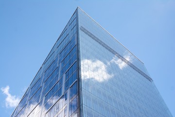 Fototapeta na wymiar Modern curtain wall made of glass and steel. Blue sky and clouds reflected in windows of modern office building. 