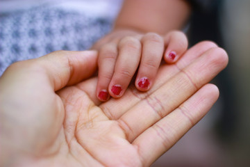 hands of a mom and her baby girl with red nails