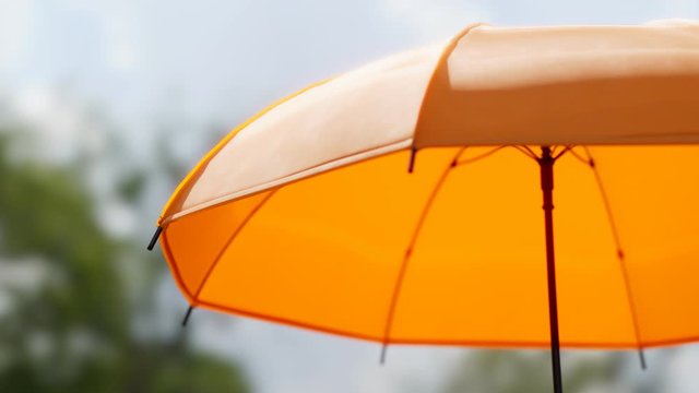 Colourful yellow umbrella spinning slowly on a sunny day. Looping animation 4KHD