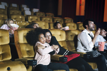 Family in the theater see movie. Mom has hug daughter and excited.
