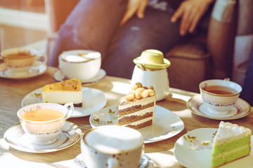 Happiness female friends meeting and drinking tea or coffee with cakes together at cafe in the afternoon. People, leisure and communication concept. Selective focus.