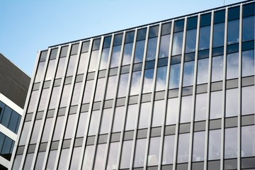 Fototapeta na wymiar Modern curtain wall made of glass and steel. Blue sky and clouds reflected in windows of modern office building. 