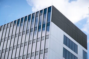 Fototapeta premium Modern curtain wall made of glass and steel. Blue sky and clouds reflected in windows of modern office building. 