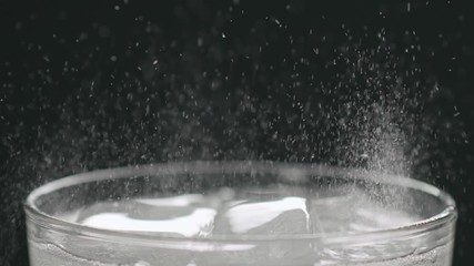 Slow motion soda in glass with ice cubes on black background closeup - Powered by Adobe