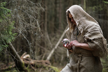 A man in a cassock spends a ritual in a dark forest