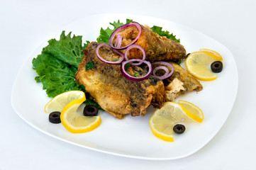 fried fish with lemon on a plate on a white background