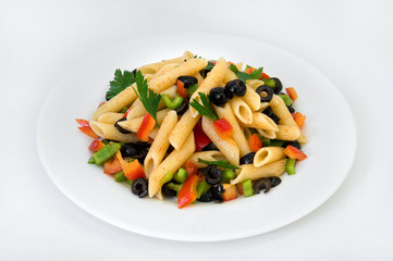 Pasta in red pepper with vegetables and olives on a plate on a white background