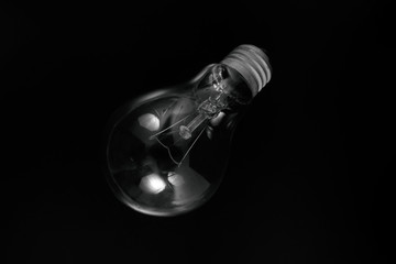 Incandescent light bulb on a black background. Front view.