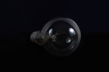 Incandescent light bulb on a black background. Front view.