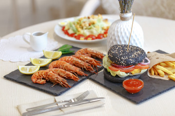 Appetizing shrimp with lemon on a black slate plate. Restaurant server of the table in the style of Provence