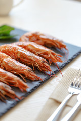 Appetizing shrimp with lemon on a black slate plate. Restaurant server of the table in the style of Provence