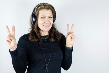 Portrait of a beautiful smiling woman with big headphones on her head. The woman listens loudly to...