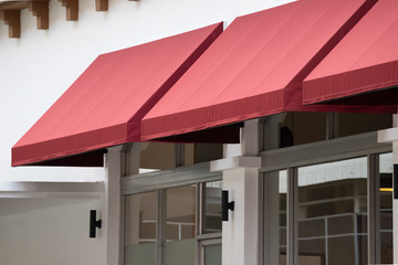 red awning over window of shop. - obrazy, fototapety, plakaty