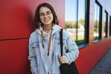Close-up portrait of cheerful pretty young 20s woman in glasses, student or employee, smiling...