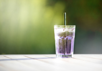 Gin Lavendel Glas auf Holztisch vor grünem Hintergrund