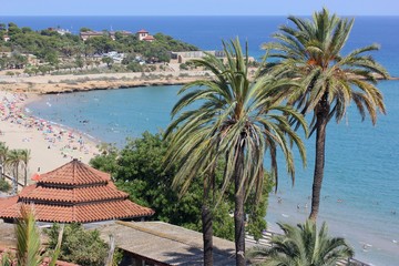 Palm trees and the Mediterranean Sea, tiled roofs of ancient European buildings - a beautiful coastal town in Spain