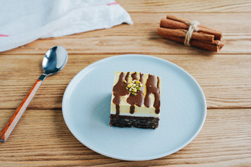 A piece of orange-chocolate cake. Spoon and cinnamon on a wooden background. Raw dessert with a nut base