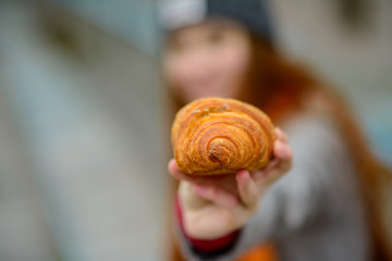 The girl holds a croissant in hand. Close-up. Selective focus