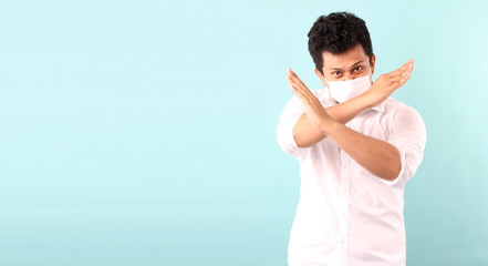 Portrait of handsome Asian man doing a stop gesture. and wearing medical mask,Recommend the prevention of viruses and various diseases. isolated on blue background in studio With copy space.