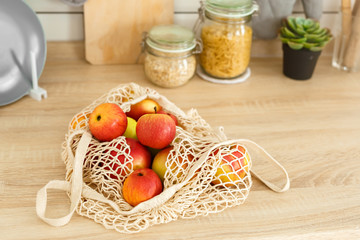 Apples in a string bag in kitchen table