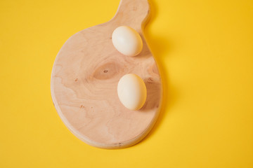 Eggs on a yellow background. Chicken eggs on a wooden board