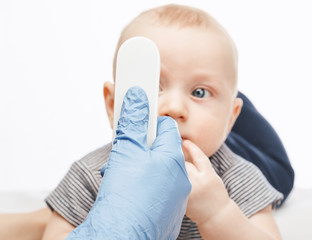 Pediatrician using infrared thermometer checking body temperature of baby boy