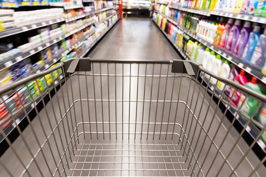 Shopping trolley cart moving in supermarket with motion blur aisle background