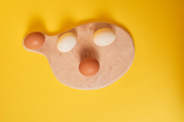 Fototapeta premium Eggs on a yellow background. Chicken eggs on a wooden board