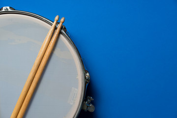 Drum stick and drum on blue table background, top view, music concept