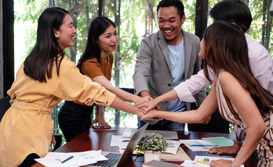 Young business people stacked hand together ,after finish working ,with colleagues team meeting,success deal,with happy feeling