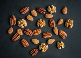 Various nuts on black wooden board, high resolution photo